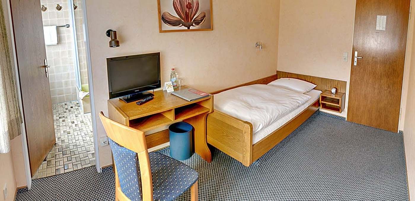 Single room with private bathroom and desk with seating and TV