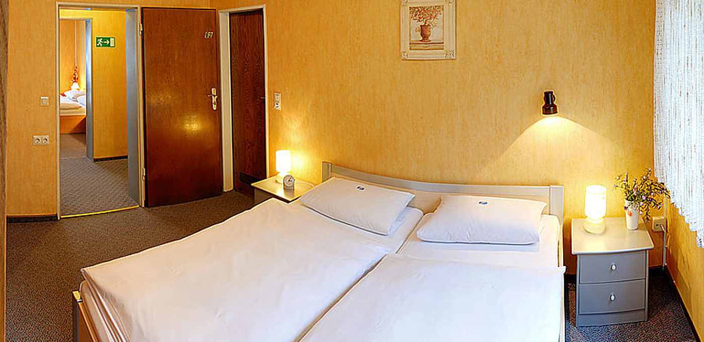 Zimmer mit gelben Wänden und einem Doppelbett neben einem Fenster