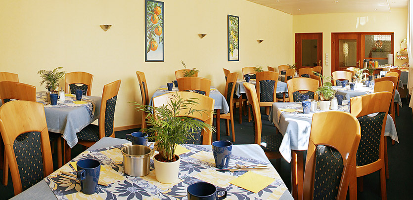 Essensraum mit gedeckten Tischen und blauem Teppichboden 